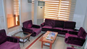 Uma sala de estar com sofás roxos, uma mesa de centro de vidro e uma revista sobre a mesa.