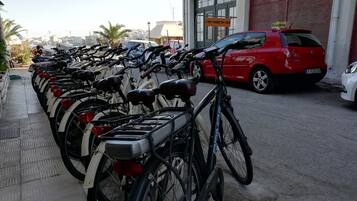 Eine Reihe von Fahrrädern, abgestellt vor einem Gebäude mit der Aufschrift 'Verleih'.