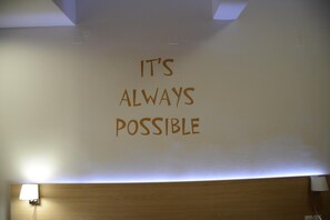A wall with the text "IT'S ALWAYS POSSIBLE" in a simple font.