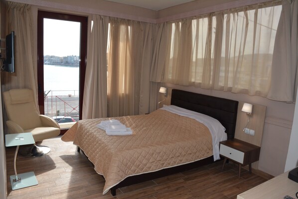 A hotel room with a bed, a chair, a small table, a nightstand, and a TV.