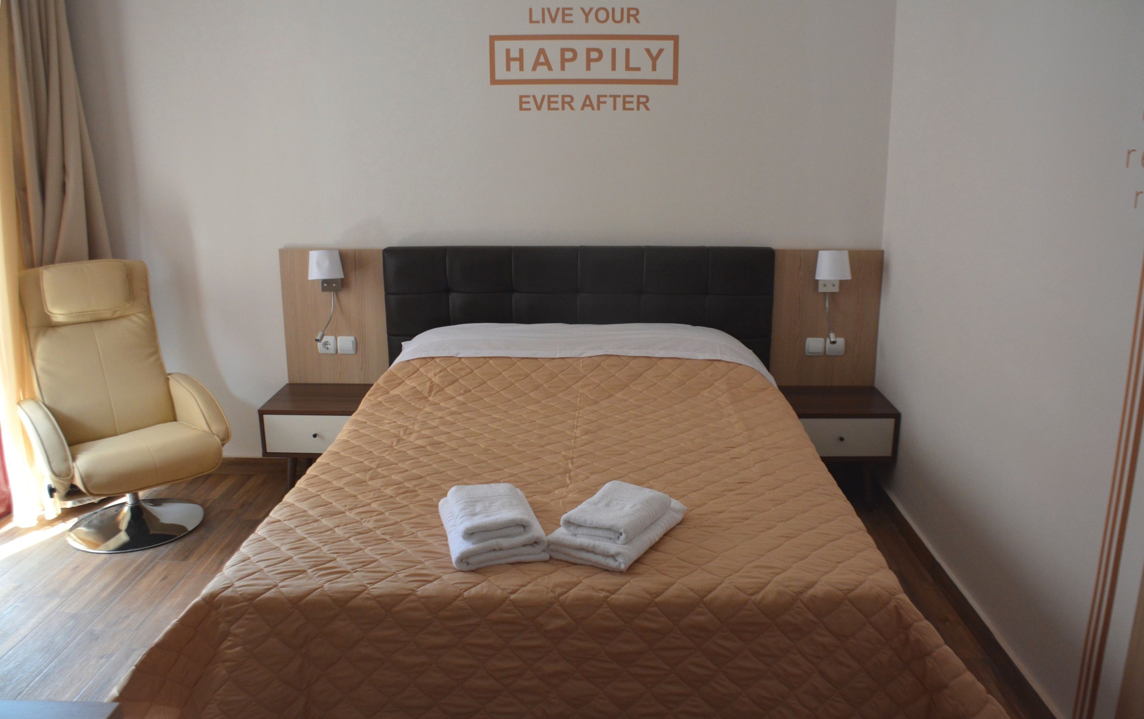 Una habitación de hotel con una cama, dos mesitas de noche, una silla y un letrero en la pared.