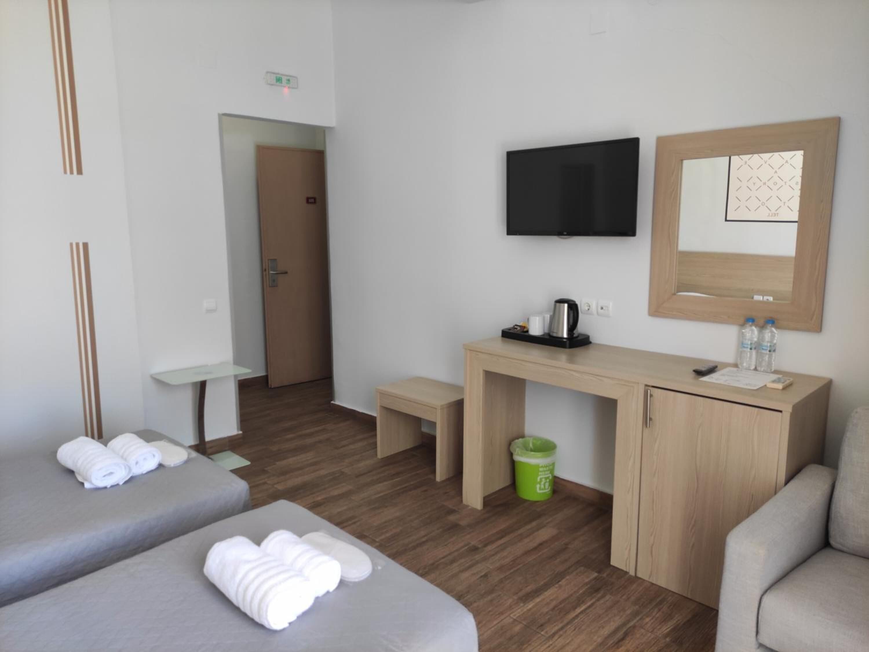 A hotel room with two beds, a desk, a TV, and a mirror.