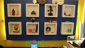 Una pared con varios estantes que exhiben diferentes objetos, como un reloj, una balanza y adornos.