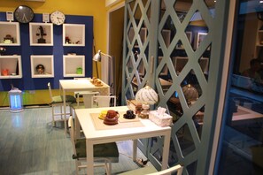 Une pièce comprenant une table, des chaises, une lampe et des étagères remplies de divers objets.