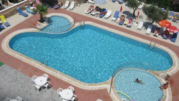 Een buitenzwembad, parasols voor strand/zwembad