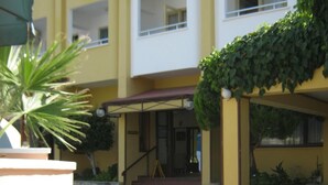 A hotel courtyard with a covered seating area, a staircase leading to the building, and a palm tree. - Oya Apartments (Kusadasi)