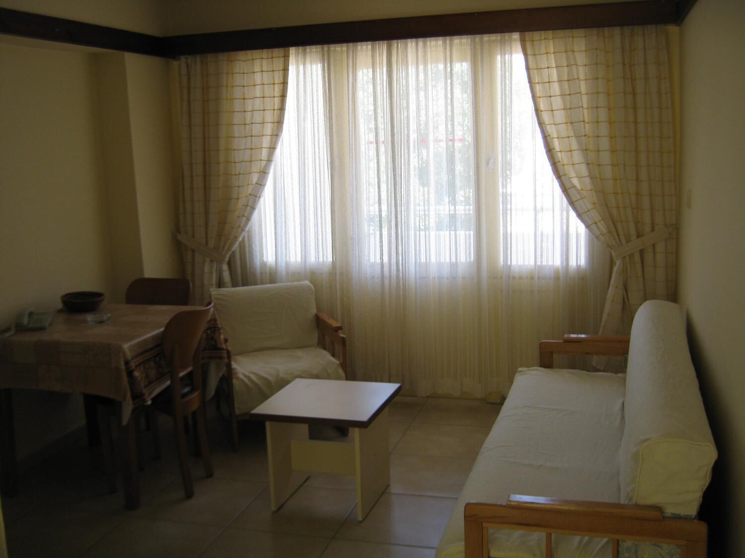 A room with a dining table, two chairs, a sofa, and a small table.