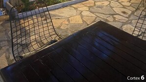 An outdoor patio area with stone flooring, metal chairs, and potted plants. - Mavi Butik Apart (Cesme)