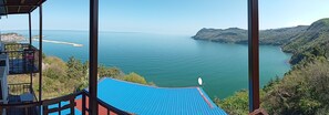 A view from a balcony overlooking a large body of water with a distant island and hills. - Gunter Seher Otel (Amasra)