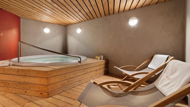 Een houten sauna met een jacuzzi en twee houten ligstoelen.