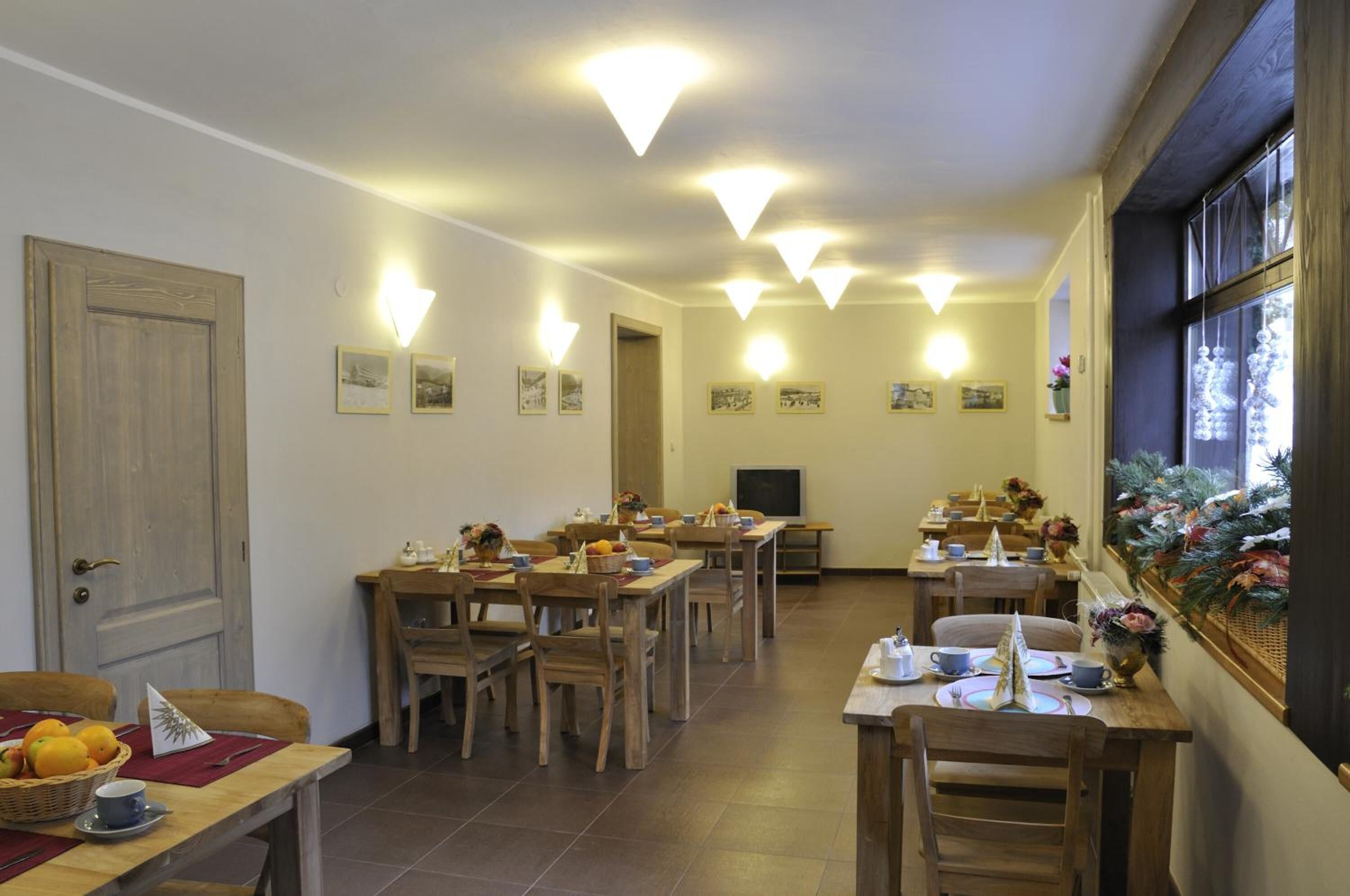 A dining area with multiple tables and chairs, a door, and wall-mounted light fixtures.
