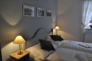 A bedroom with two beds, a nightstand with a lamp, and three framed pictures on the wall. - Grand Apartments (Spindleruv Mlyn)