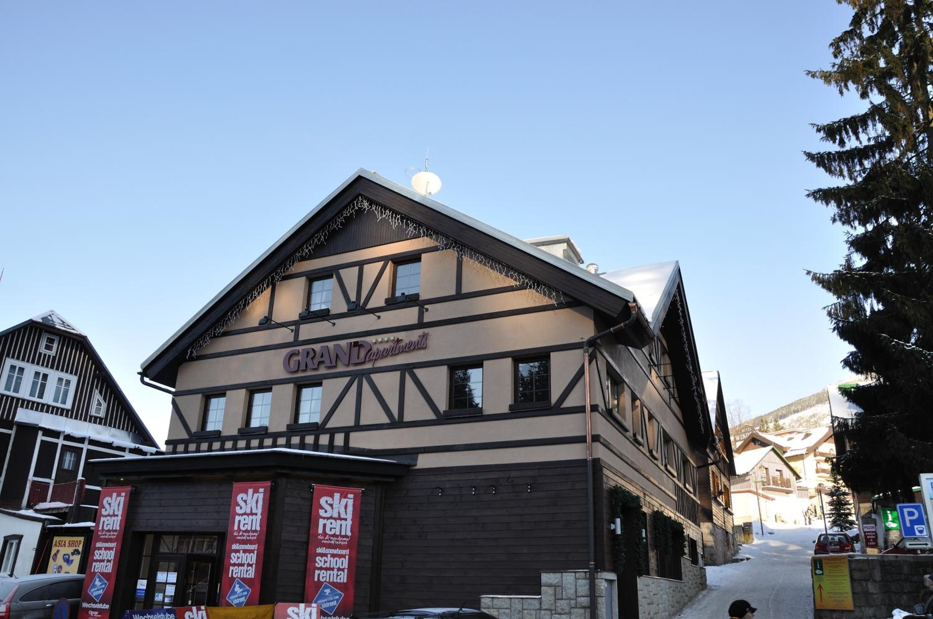 A building with a sign reading "GRAND Apartments" and multiple "ski rental" signs.