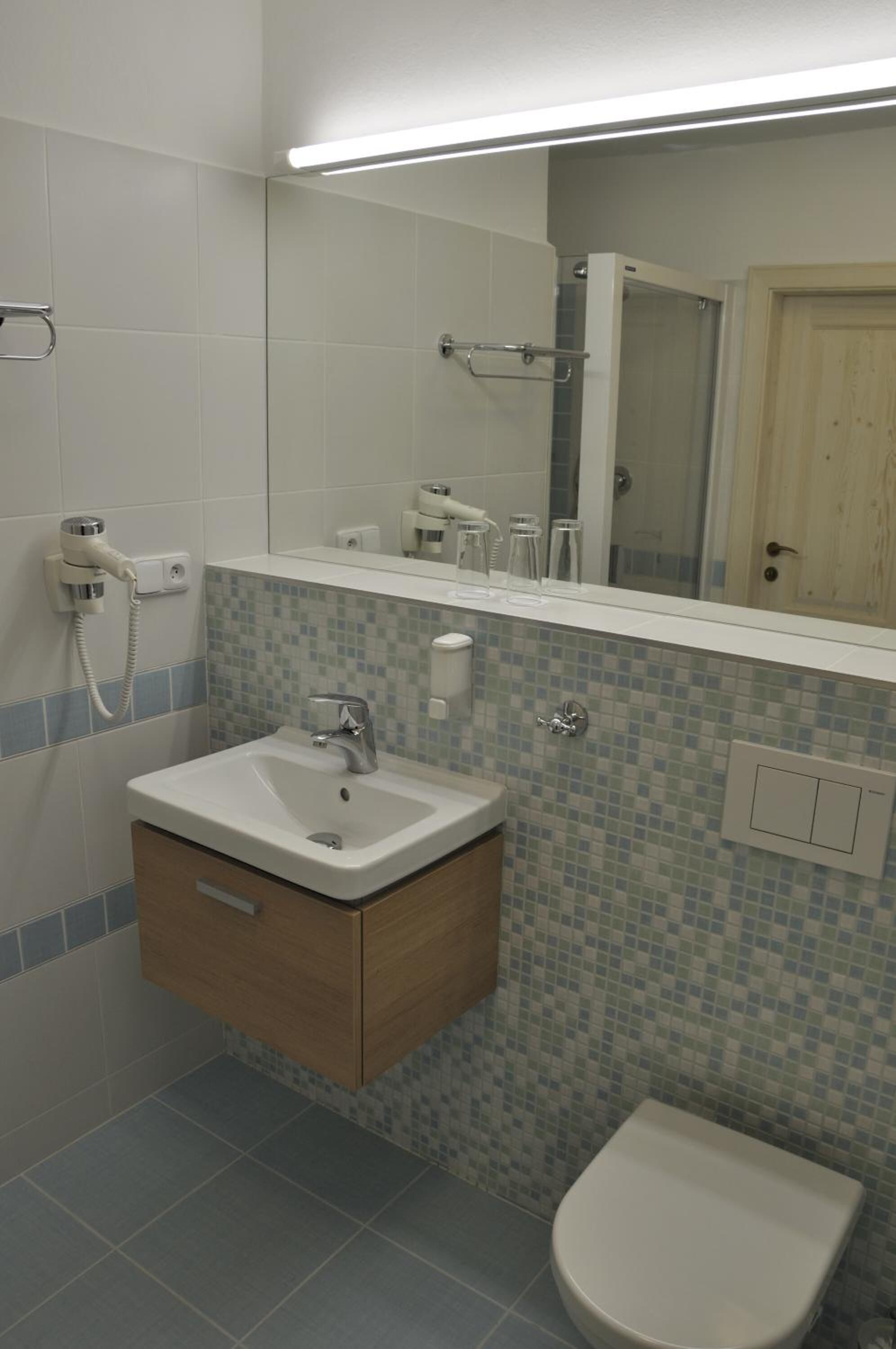 A bathroom with a white sink, a mirror, and a toilet.