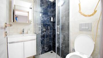 A modern bathroom with a glass-enclosed shower, a white sink, and a toilet.