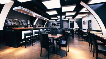 A modern bar area with a variety of liquor bottles, black leather chairs, and tables.