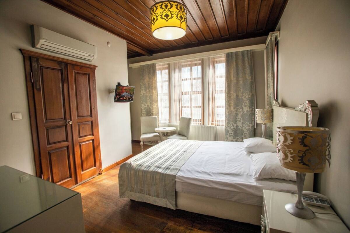 A bedroom with a bed, a bedside lamp, a chair, a small table, and a wardrobe.