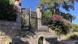 A stone staircase leading to a gated entrance with a wrought iron gate, surrounded by lush greenery and flowering plants. - Portofino Boutique Hotel (Ula)