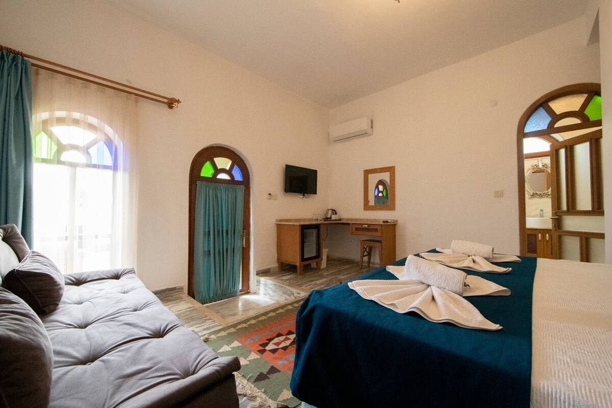 A hotel room with a bed, a desk, a television, and a window with curtains.