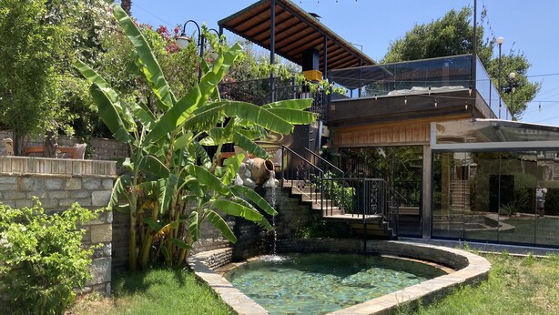 A modern house with a stone staircase leading to a wooden deck, a swimming pool, and lush greenery. - Portofino Boutique Hotel (Ula)