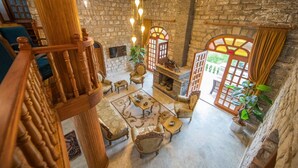 A spacious room with a stone wall, a fireplace, and a wooden staircase. - Portofino Boutique Hotel (Ula)