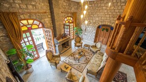 A spacious room with a stone wall, a fireplace, and a wooden staircase. - Portofino Boutique Hotel (Ula)