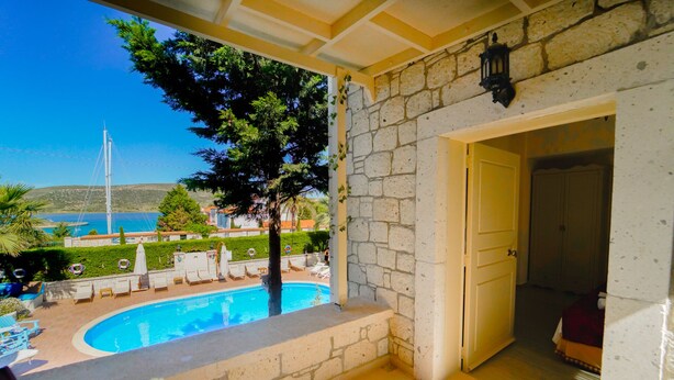 Un balcon avec piscine, des murs en pierre et une vue sur la mer et les collines.