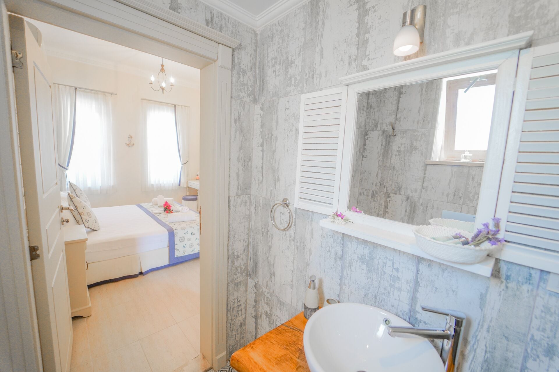 Un baño con pared de mármol, un lavabo blanco y un espejo encima.