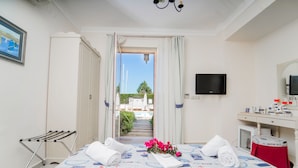 Une chambre d’hôtel équipée d’un lit, d’une télévision, d’un bureau et offrant une vue sur une piscine et les bâtiments environnants.