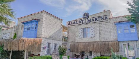 A building with the sign 'Alacati Marina Palace' and a swimming pool in front.