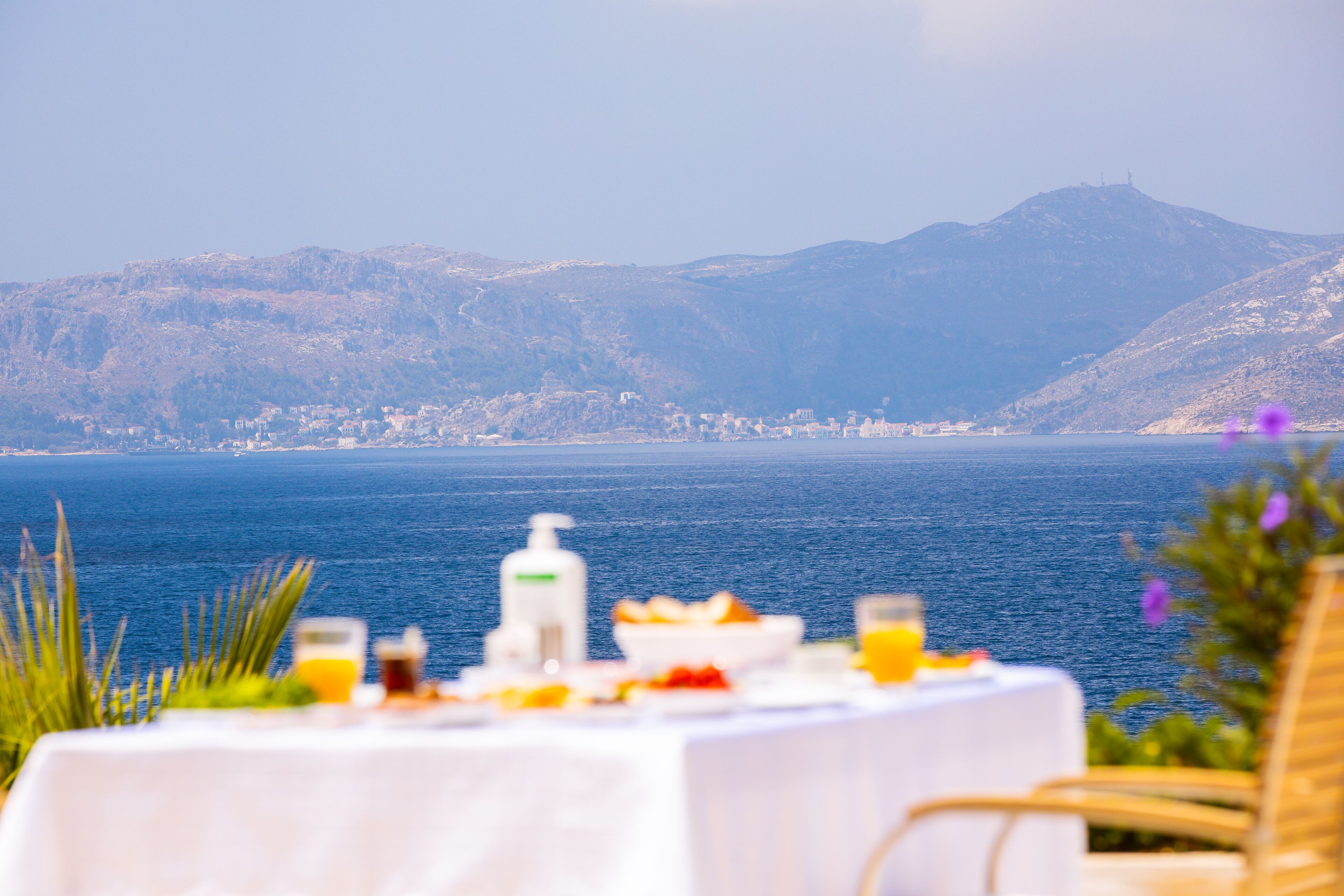 A table set with breakfast items and a view of the sea and mountains.