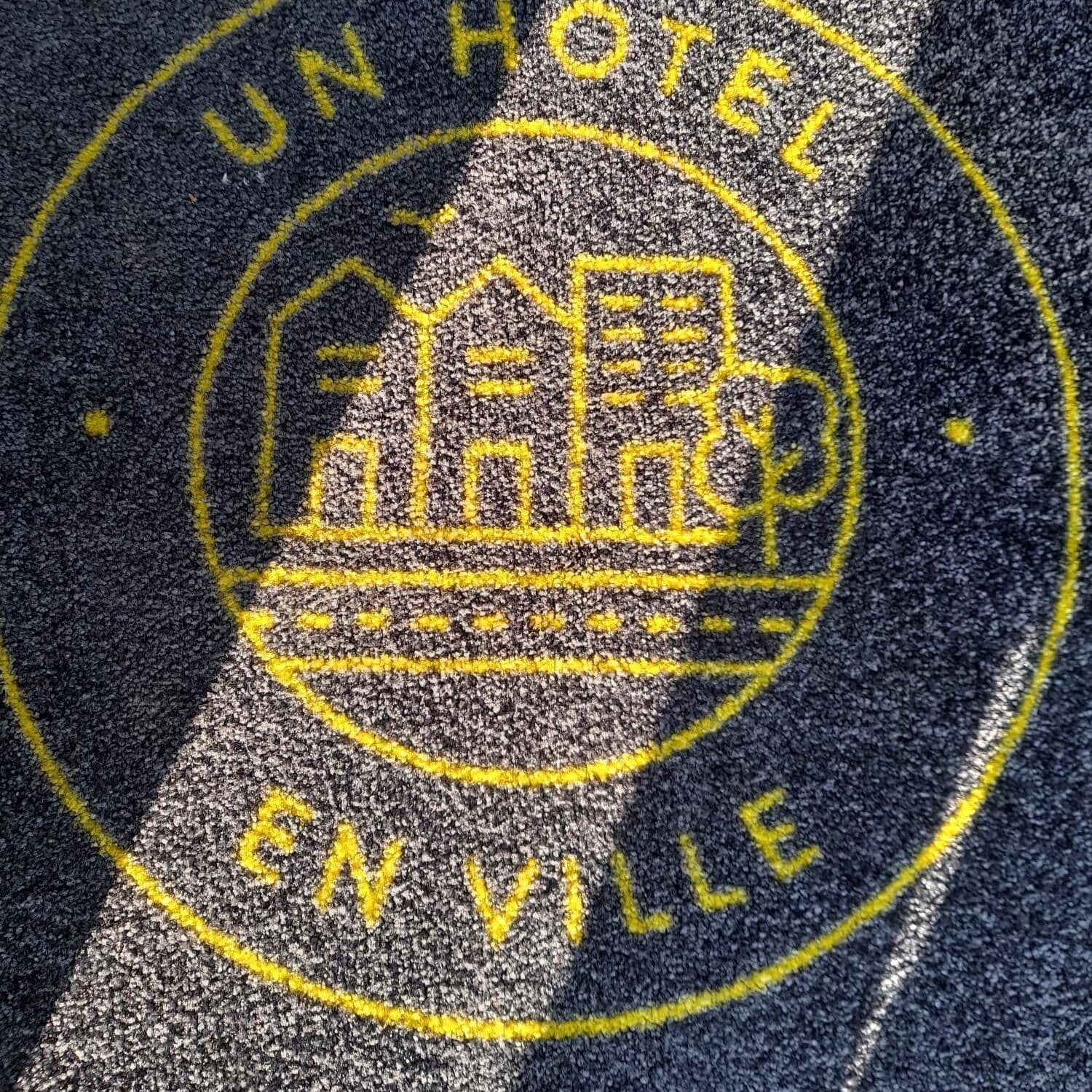 A hotel emblem with a building and the text "UN HOTEL EN VILLE".