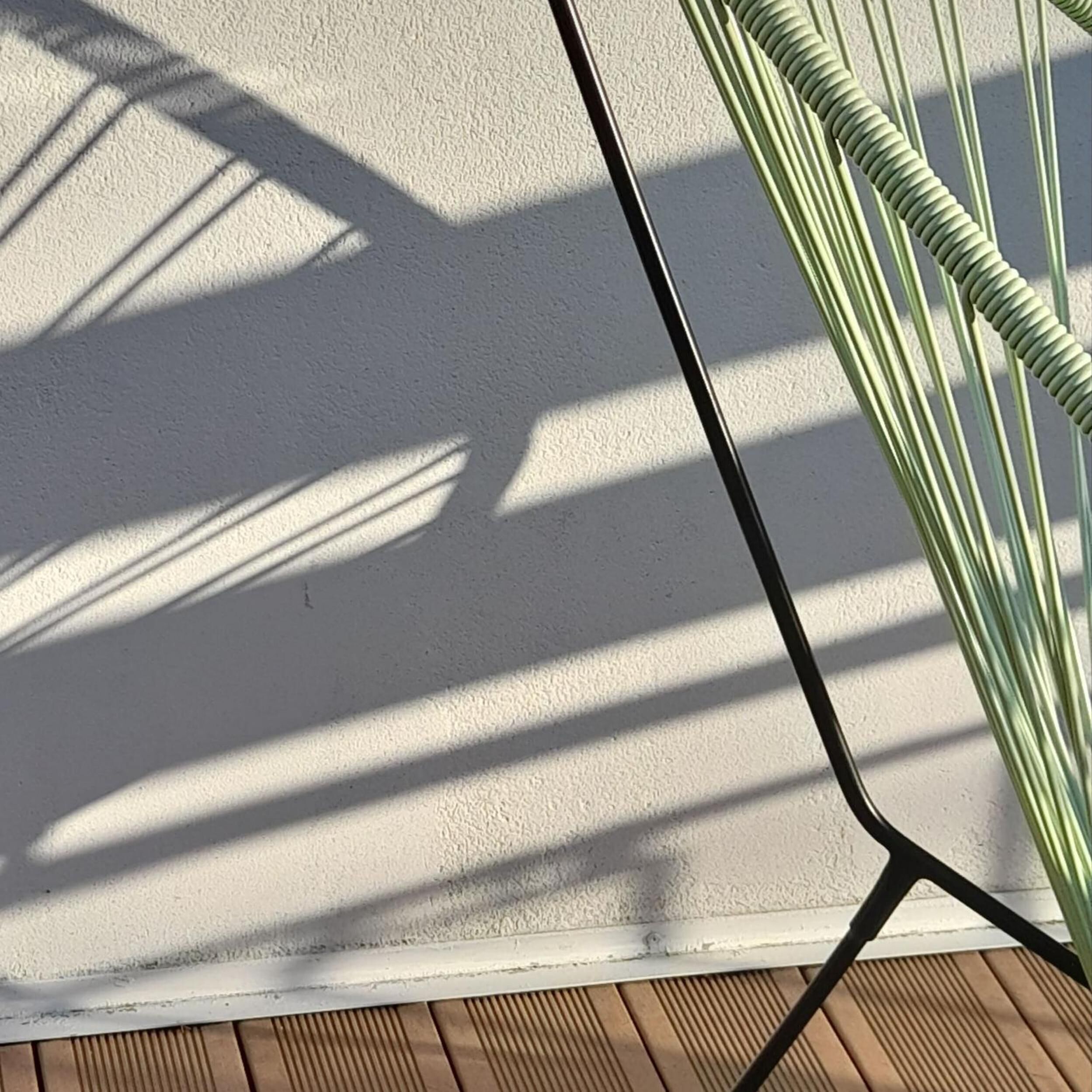 A white wall with shadows cast by window blinds.