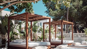 A serene outdoor spa area with wooden canopy beds and lush tropical plants.