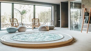 A modern spa room with a hot tub, wicker chairs, and a view of the outdoors.