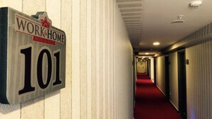 Un pasillo con un letrero que dice "WORK&HOME 101" y una alfombra roja.