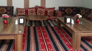 Una habitación con un conjunto de sofá, dos mesas de madera y alfombras estampadas.