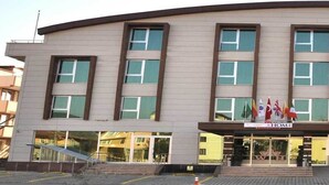 Un edificio moderno con fachada curva, múltiples ventanas y una entrada central con un letrero.