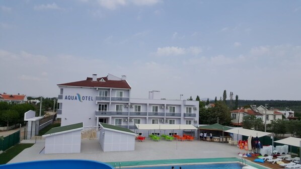 A hotel with a swimming pool, outdoor seating, and a view of the surrounding area.