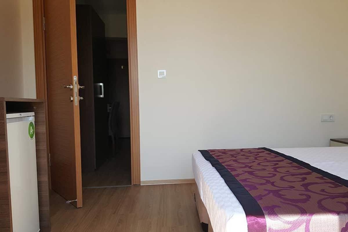 Una habitación de hotel con una cama, un armario y una puerta que da a un baño.