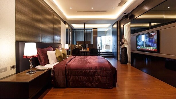 A modern hotel room with a large bed, a TV, and a desk with a lamp. - Leedon Motel (Kaohsiung)