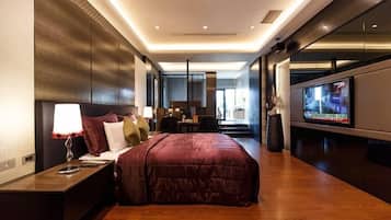 A modern hotel room with a large bed, a TV, and a desk with a lamp.
