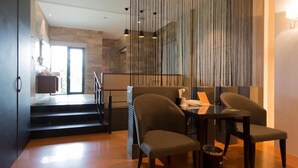 A modern dining area with a glass partition, a table with chairs, and a staircase leading to an upper level. - Leedon Motel (Kaohsiung)