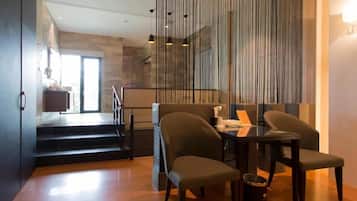 A modern dining area with a glass partition, a table with chairs, and a staircase leading to an upper level.