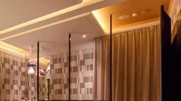A hotel room with a checkered wall pattern, a bed, two armchairs, a table, and a large mirror.