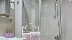 A bathroom with a glass-enclosed shower, a white sink, and a pink towel rack.