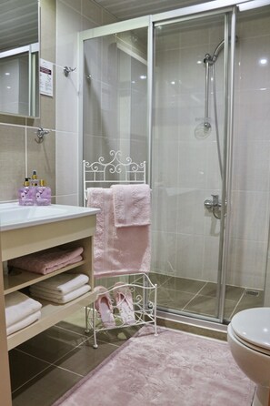 Bathroom features a glass-enclosed shower, sink, toilet, and towel rack.