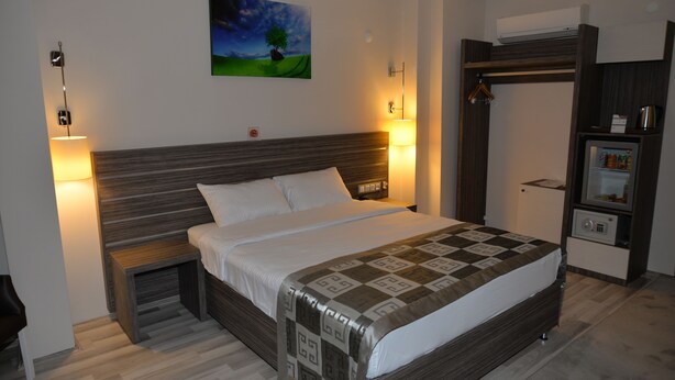 A bedroom with a bed, bedside tables, a wardrobe, and a painting on the wall.