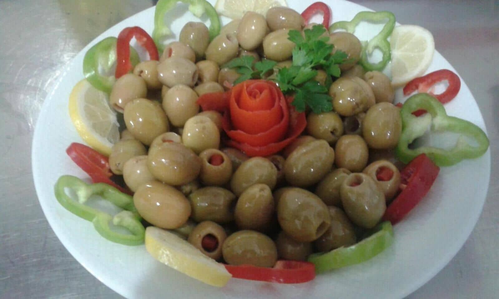 A plate of olives, red bell peppers, and lemon slices.