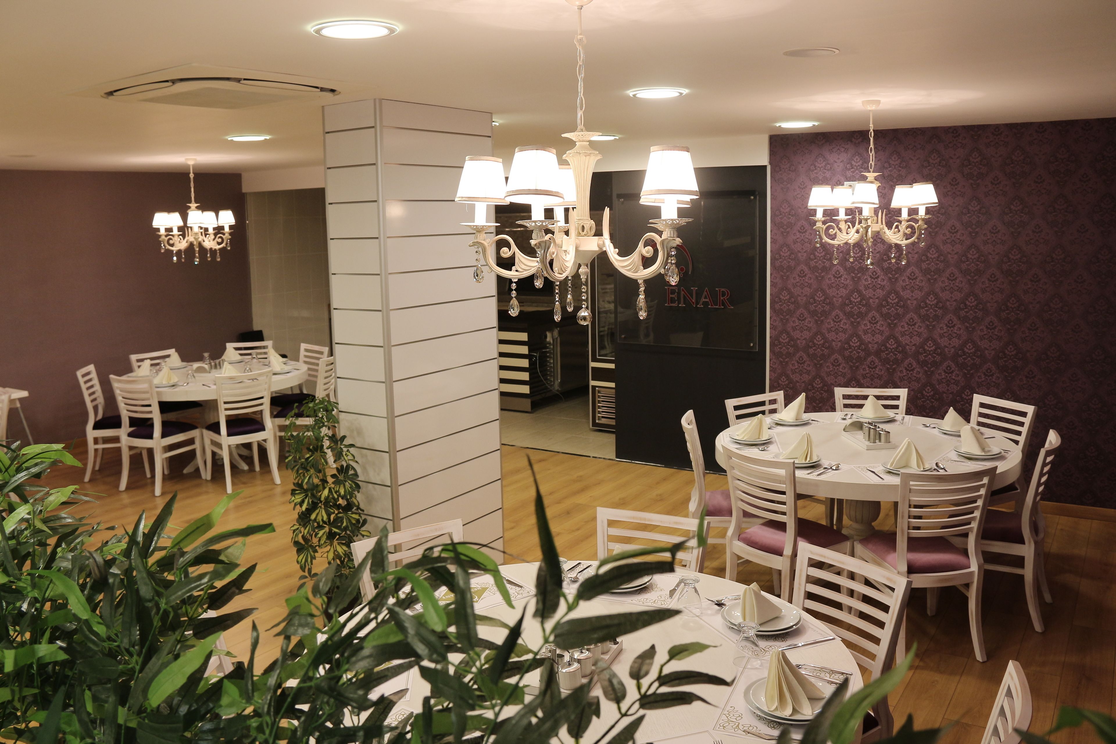 Comedor con mesas redondas, sillas blancas y candelabros.